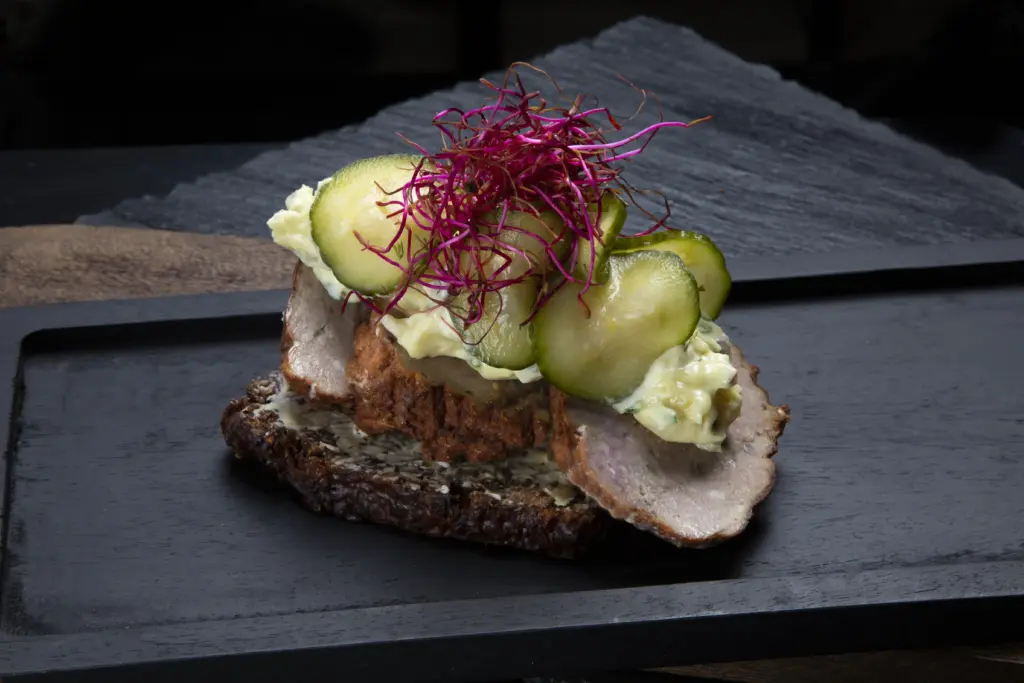 Smørrebrød med frikadelle på rugbrød fra Ibens Smørrebrød i København med hjemmelavet remoulade, sprøde syltede agurker og spirer