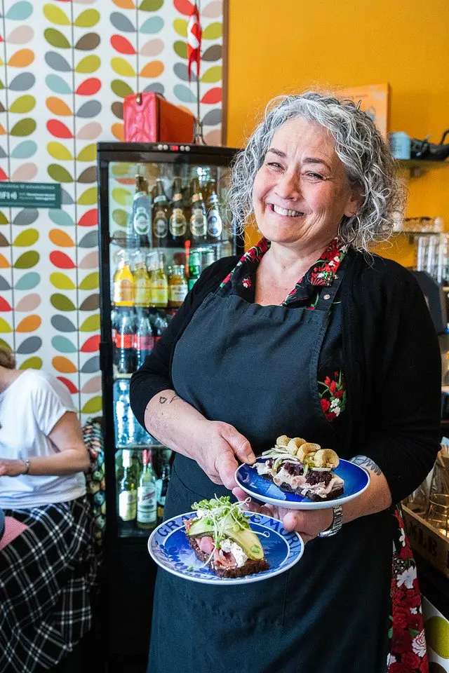 Restauratør Iben Herrik serverer smørrebrød for sine gæster med et smil