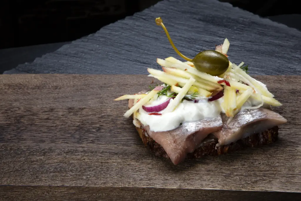 Smørrebrød med marineret sild på rugbrød fra Ibens Smørrebrød i København med karrysildesalat, økologiske æg, rødløg, kapers og karse