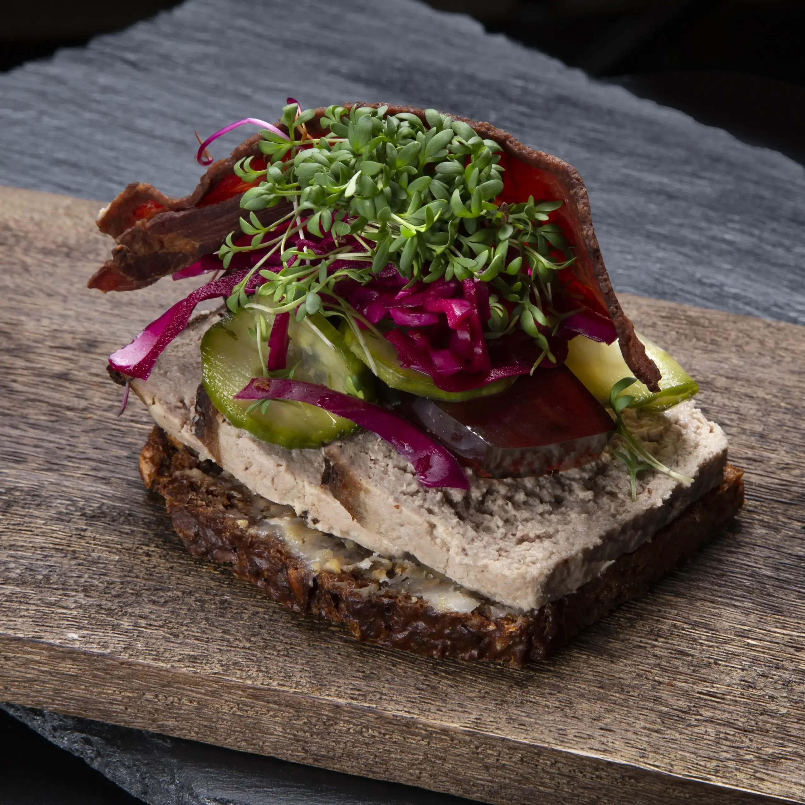 Smørrebrød med leverpostej på rugbrød fra Ibens Smørrebrød i København med hjemmesyltede agurker, rødkål, sprød bacon og karse