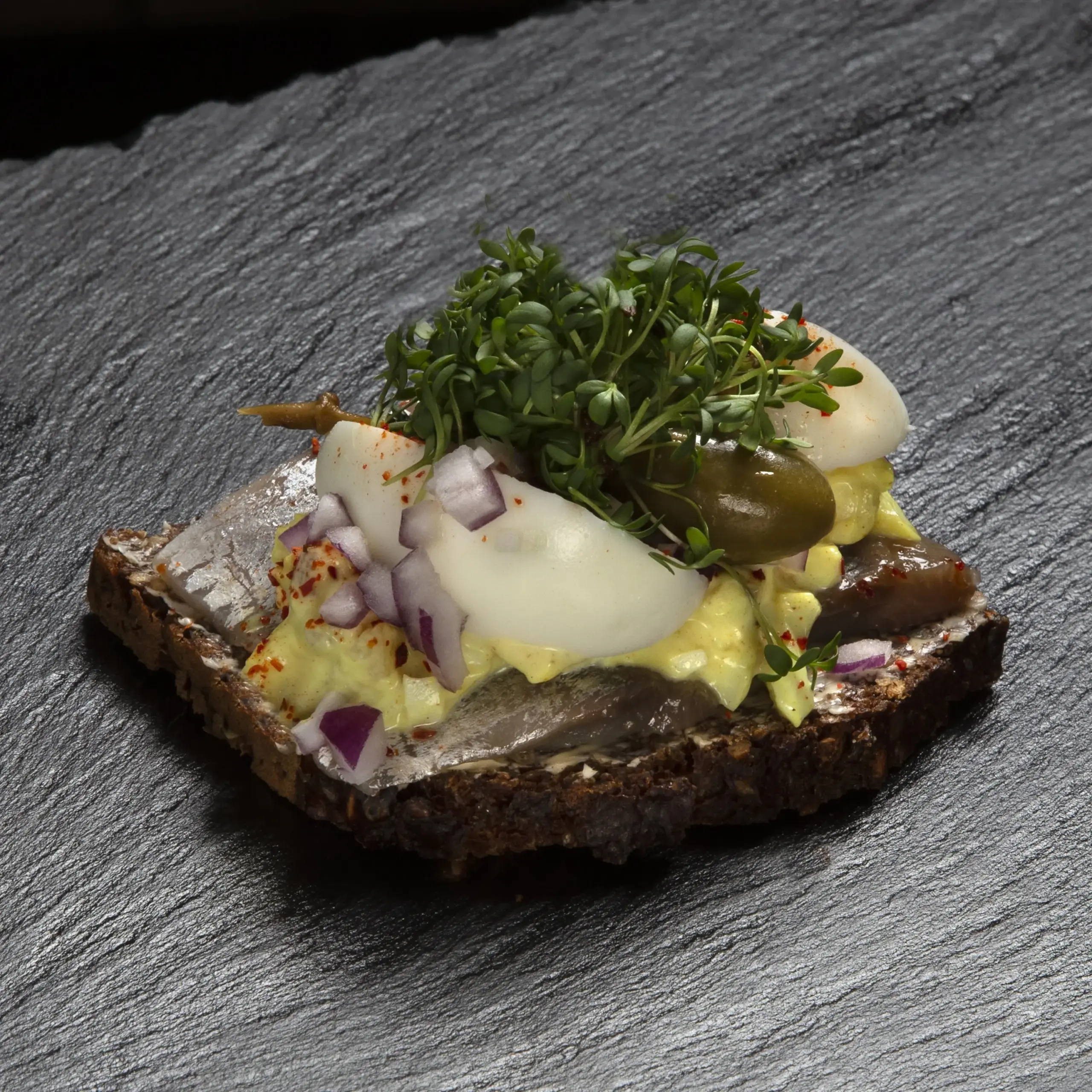 Smørrebrød med marineret sild på rugbrød fra Ibens Smørrebrød i København med karrysalat, økologiske æg, rødløg, kapers og karse