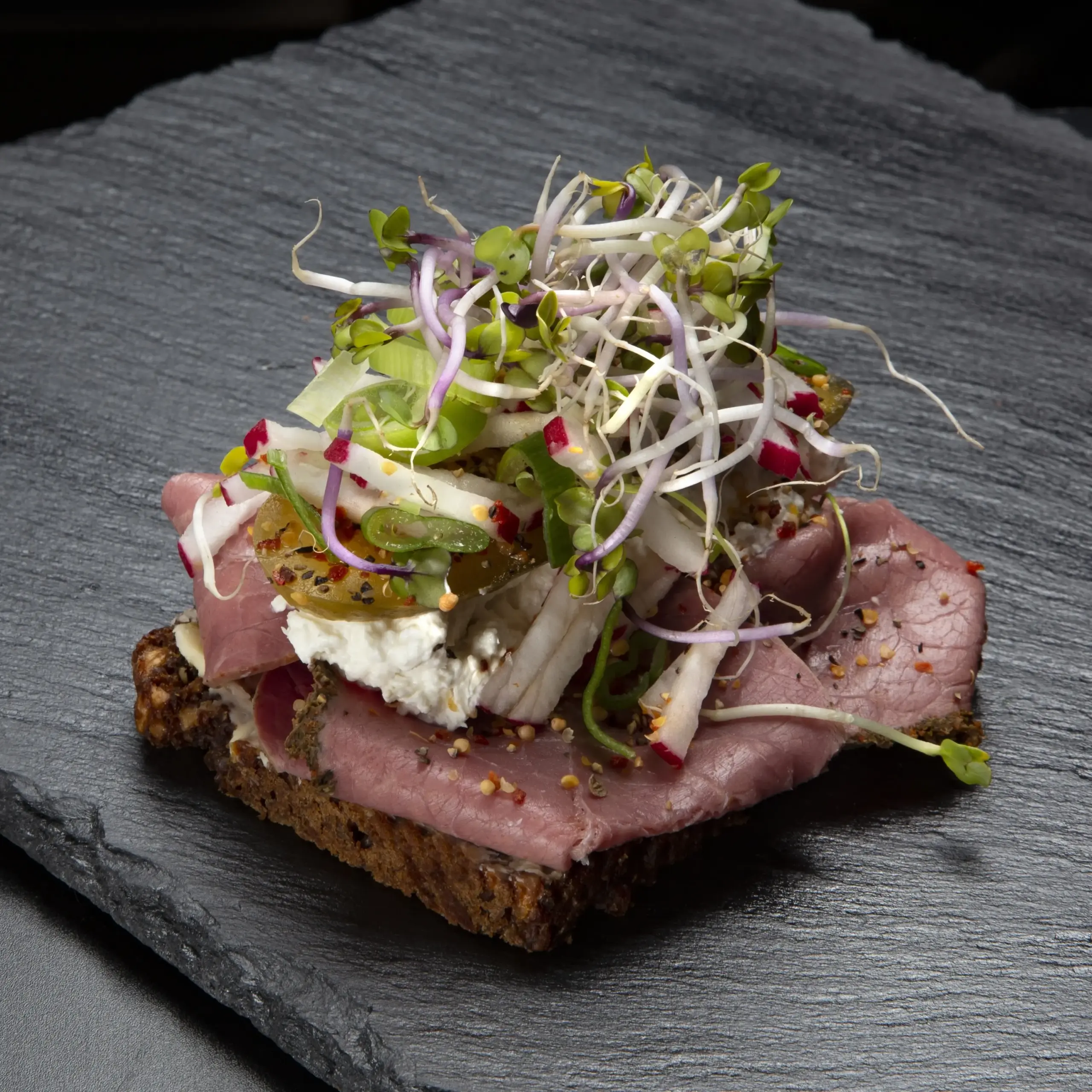 Smørrebrød med pastrami på rugbrød fra Ibens Smørrebrød i København med peberrodscreme, radiser, grønt og spirer