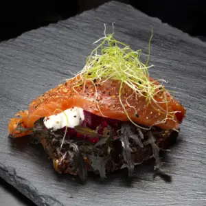 Smørrebrød med røget laks på rugbrød fra Ibens Smørrebrød i København med mizunasalat, rødbedetatar, rygeostcreme, grov peber og spirer