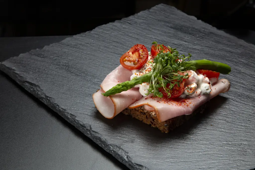 Smørrebrød med røget dansk skinke på rugbrød fra Ibens Smørrebrød i København med italiensk salat, sprøde asparges, tomat, piment d’Espelette og karse